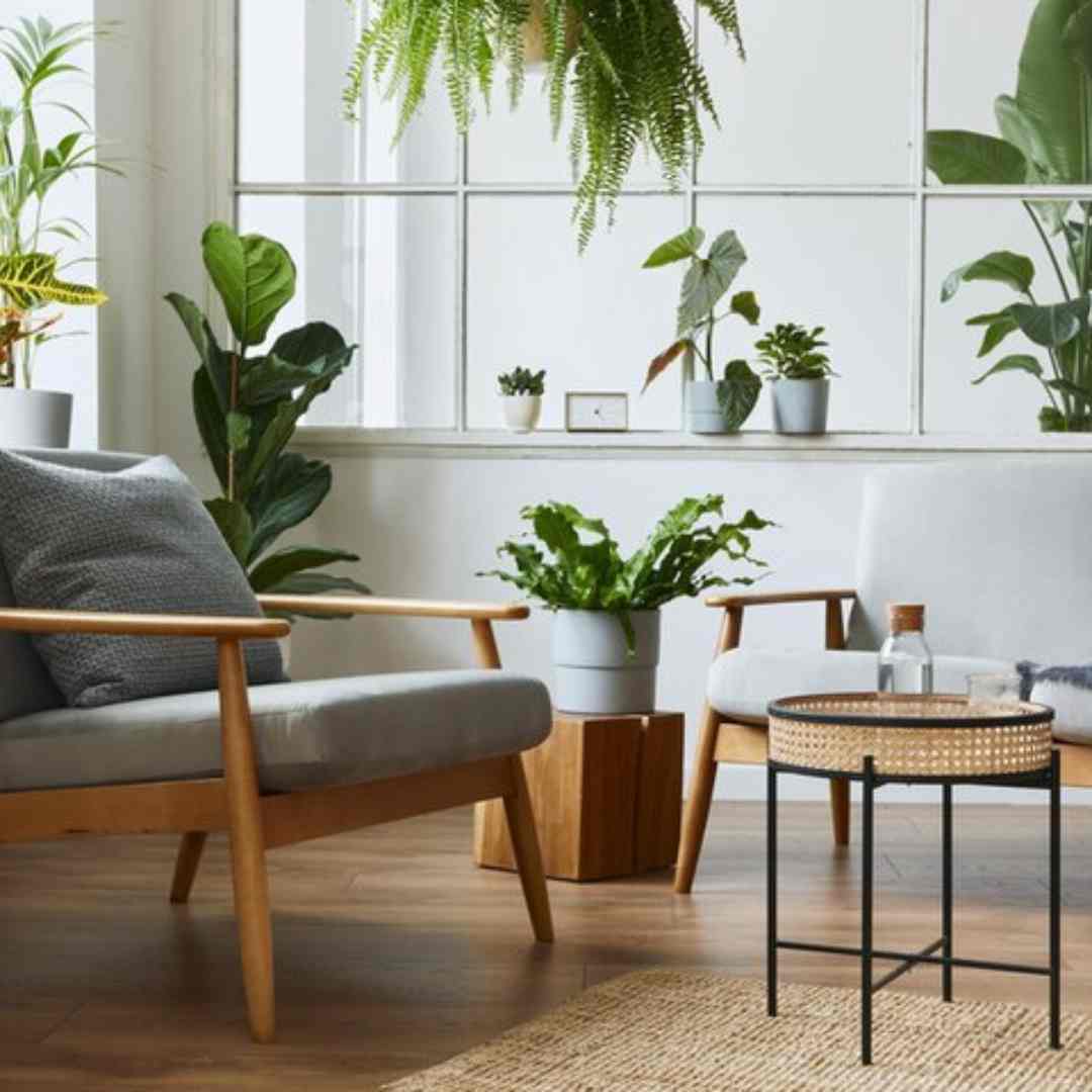 Escritório integrado à natureza, com funcionários trabalhando em meio a plantas verdes e jardins verticais. Janela com vista para paisagem natural. Ambiente inspirador que favorece o bem-estar e a criatividade dos colaboradores.